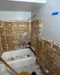 A bathroom undergoing renovation, showing stripped walls and an old bathtub by Make It Happen Homes STL in St. Louis, MO.