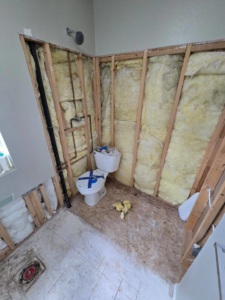A bathroom undergoing demolition and renovation, showing exposed studs and plumbing, by Fullhouse Builders LLC in Gig Harbor, WA
