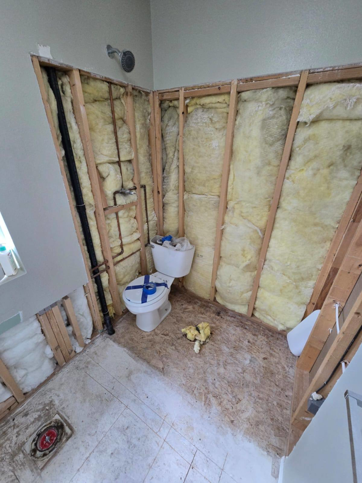 A bathroom undergoing demolition and renovation, showing exposed studs and plumbing, by Fullhouse Builders LLC in Gig Harbor, WA