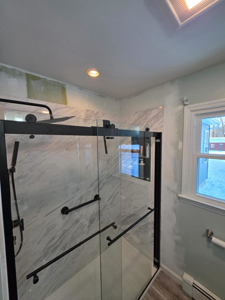 A bathroom renovation in progress, showing exposed drywall and wall patching near a shower by Precision Property Services LLC in South Windsor, CT.