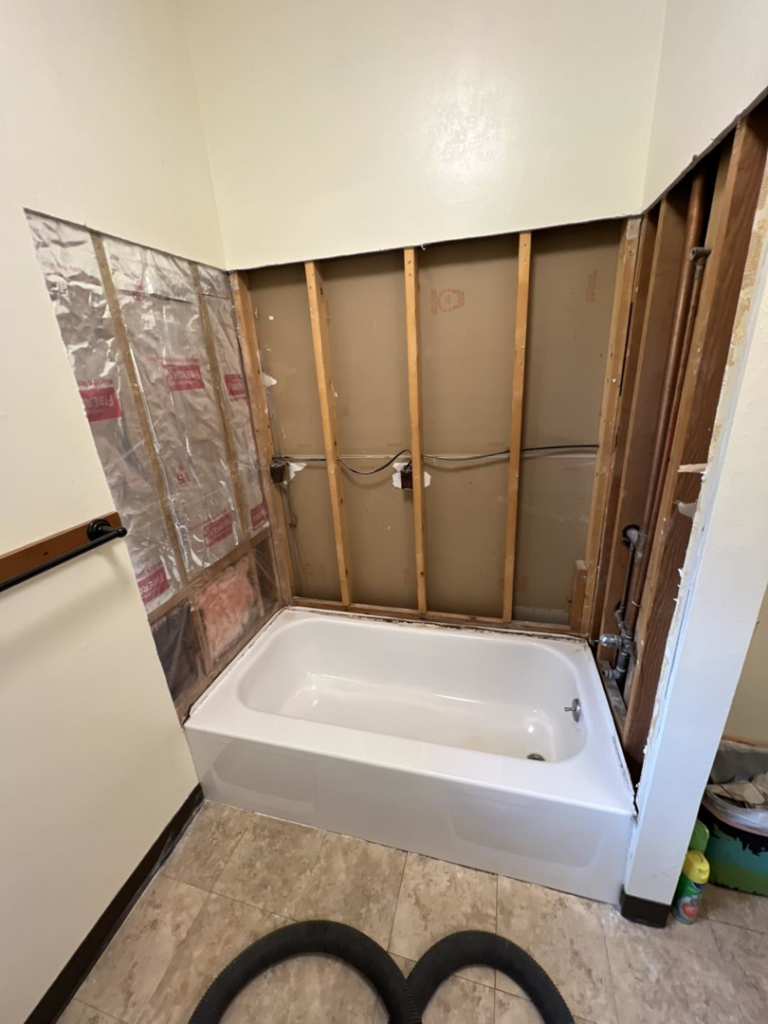 Bathroom renovation in progress with exposed studs and plumbing around a new bathtub by JKM Services in Solon, OH.