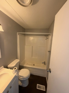 A clean, renovated bathroom with a new toilet, vanity, and shower-tub combination installed by Hard Knox Handyman in Knoxville, TN.