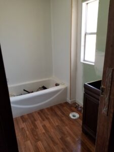 A bathroom undergoing renovation with new flooring, a bathtub, and a vanity being installed by Lee's Handyman Service LLC in Oxford, MS.