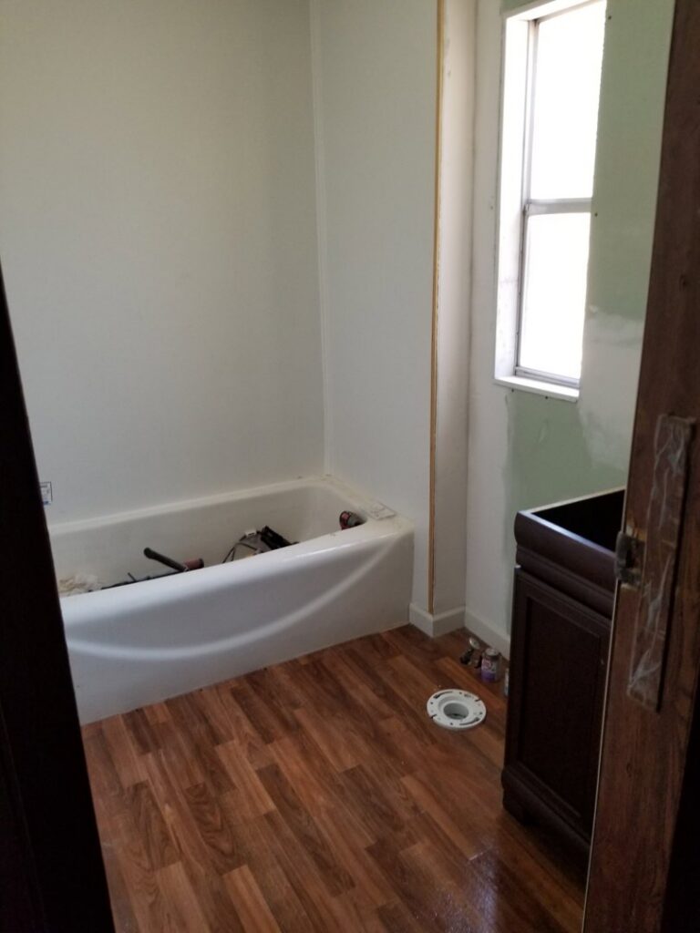 A bathroom undergoing renovation with new flooring, a bathtub, and a vanity being installed by Lee's Handyman Service LLC in Oxford, MS.