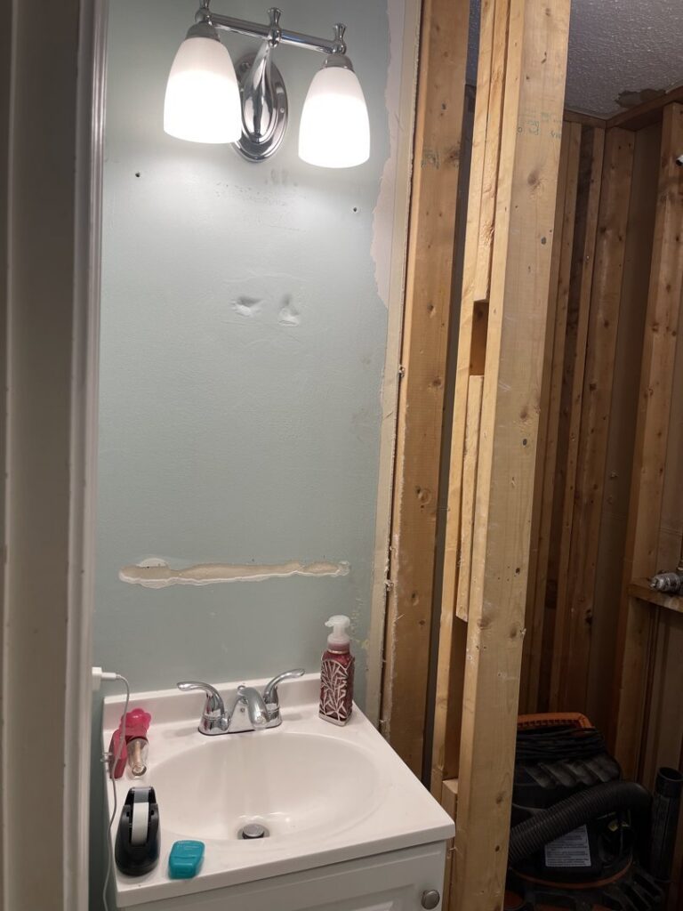 A bathroom renovation in progress, showing exposed framing and a vanity installation by Granite State Handyman & Home Repair in Derry, NH.