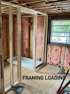 A bathroom renovation project in progress, showing new wooden framing, insulation, and a shower pan installation by NOAT in North Providence, RI.