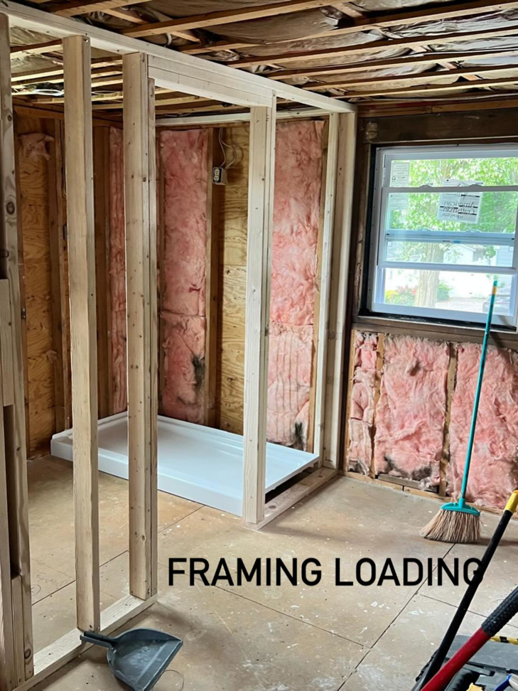 A bathroom renovation project in progress, showing new wooden framing, insulation, and a shower pan installation by NOAT in North Providence, RI.