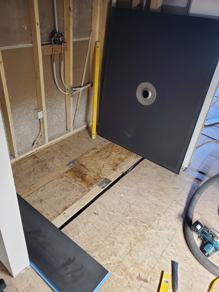 Bathroom renovation showing exposed wall studs, plumbing, and a shower pan ready for installation by Tile Works inc in Naperville, IL.