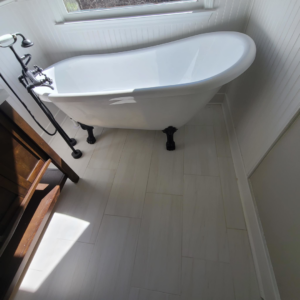 A newly renovated bathroom featuring a white freestanding tub and modern tile flooring by Stonehedge Construction in Buford, GA