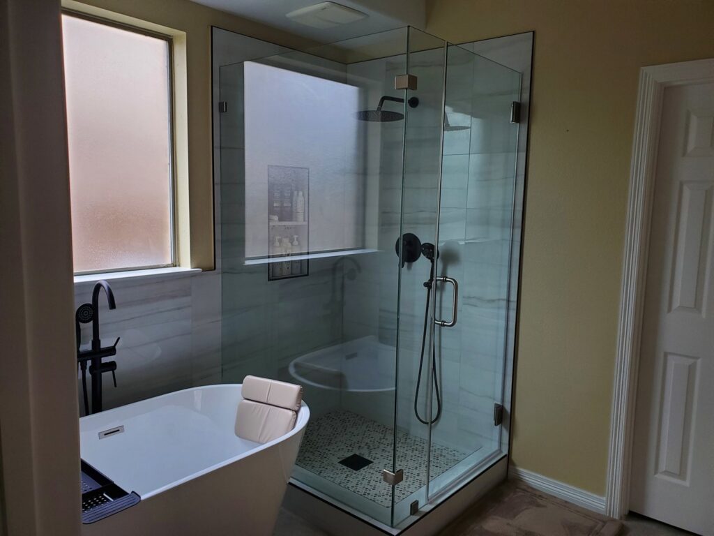 A modern bathroom renovation featuring a freestanding tub and a glass-enclosed shower by MC Master Construction in League City, TX