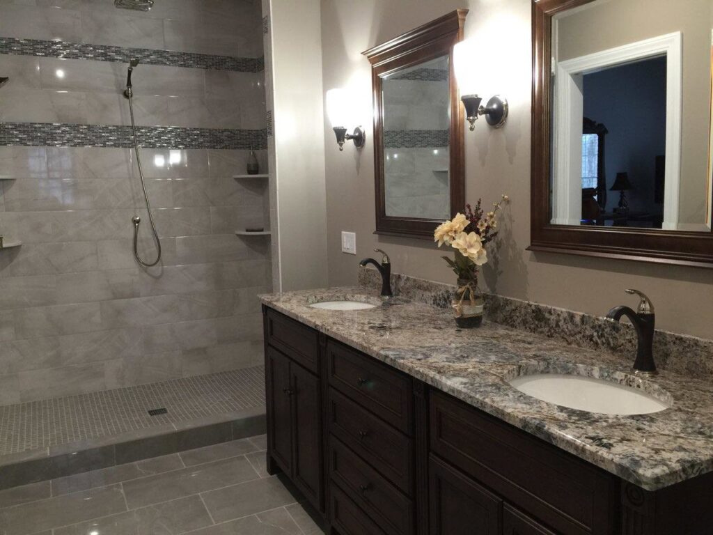 A completed bathroom renovation featuring a double vanity with granite countertops and a tiled walk-in shower by Adam Ross Cut Stone in Albany, NY.