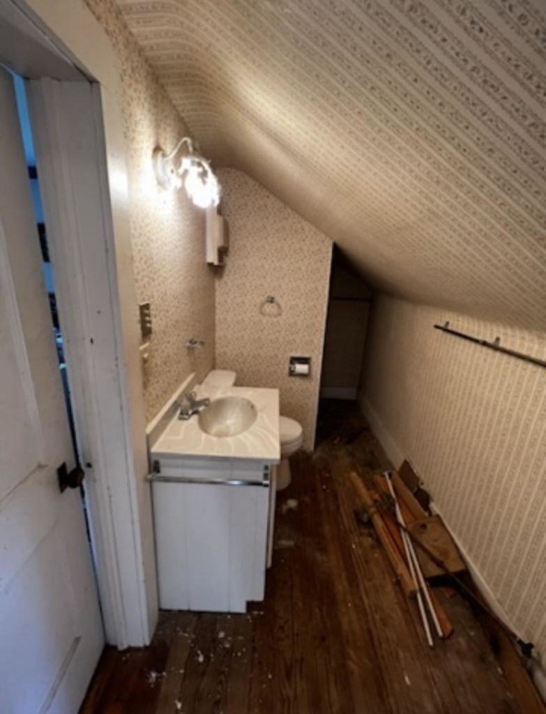A bathroom undergoing renovation with old wallpaper and debris, a project by Bill's Handyman Services in Anchorage, AK.