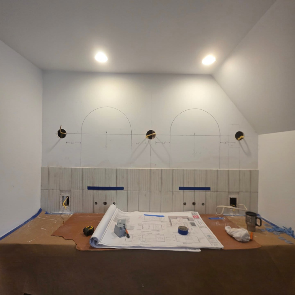 A bathroom renovation in progress with tiling and blueprints, showcasing Ember Works' general contractor services in Rochester, NY.