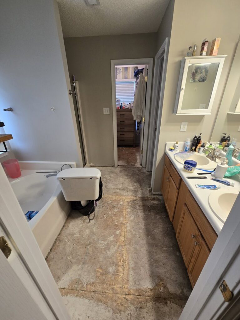 A bathroom undergoing renovation, showing the subfloor and removed vanity, by Home FREA in Raleigh, NC.