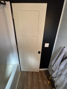 A bathroom renovation in progress with new door, flooring, and wall paneling by J Webb's Home Improvements LLC in Peoria, IL.