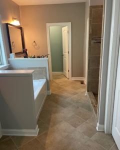 A bathroom renovation in progress showing a bathtub, tiled floor, and shower stall with tools by KACE Construction in Nashville, TN.
