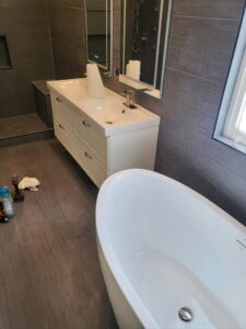 A bathroom renovation in progress, showing a new vanity, freestanding tub, and tools on the floor by Mr. Affordable LLC in Denver, CO.