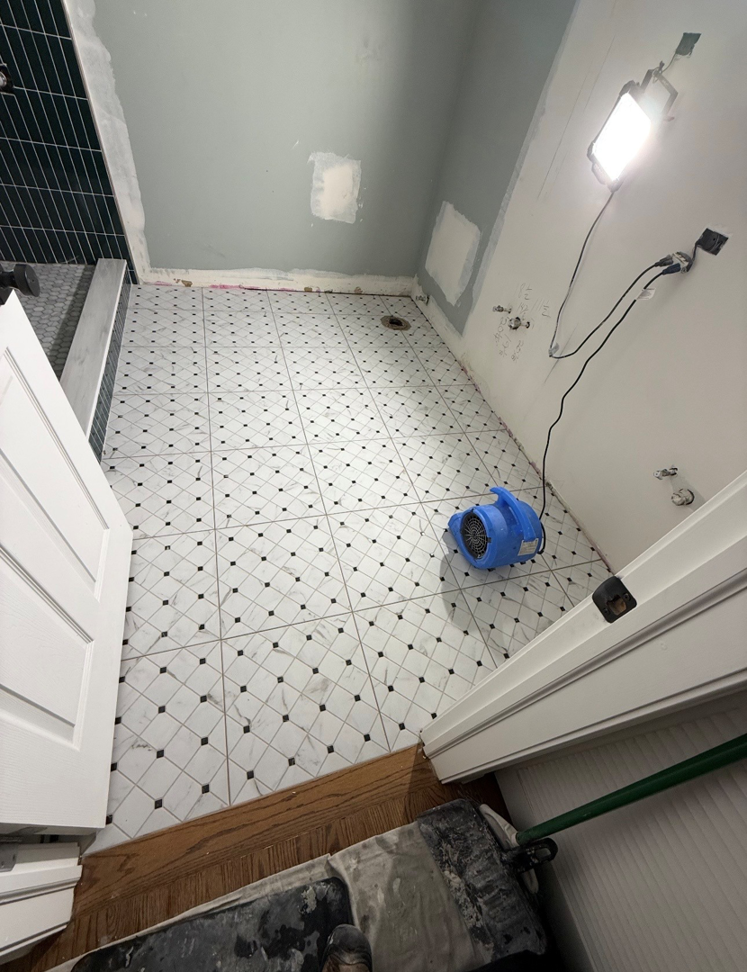 A bathroom renovation in progress with new patterned floor tiles and unfinished walls by All In Service Group, LLC in Chicago, IL.