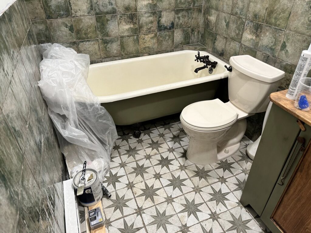 A bathroom renovation in progress, showing a covered bathtub, new toilet, and patterned floor tiles by Tile Jawn in Philadelphia, PA.