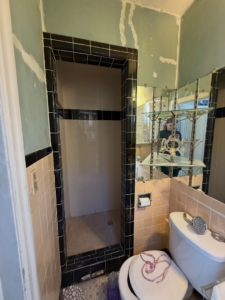 A bathroom undergoing renovation, showing prepped walls and old tiles by Waking Up Construction in Oklahoma City, OK.