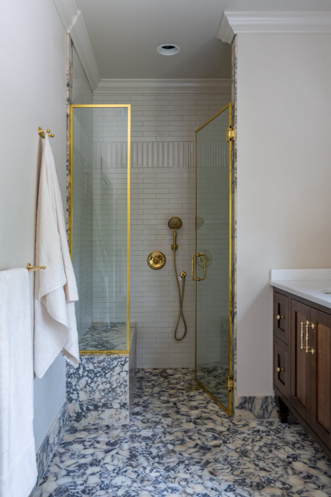 A renovated bathroom featuring a marble shower, gold fixtures, and a new vanity by Kyle Build in Chattanooga, TN.