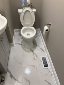 A newly renovated bathroom featuring new floor tiles, toilet, and vanity installed by Unto GOD's Kingdom Builders in Mint Hill, NC.