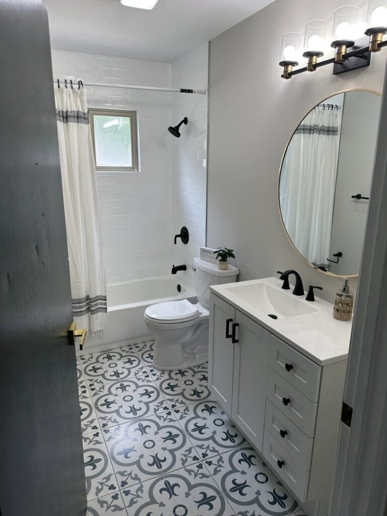 A renovated bathroom featuring patterned floor tiles, a new vanity, and a shower/tub combo by Enjaycee Unlimited in Cincinnati, OH.