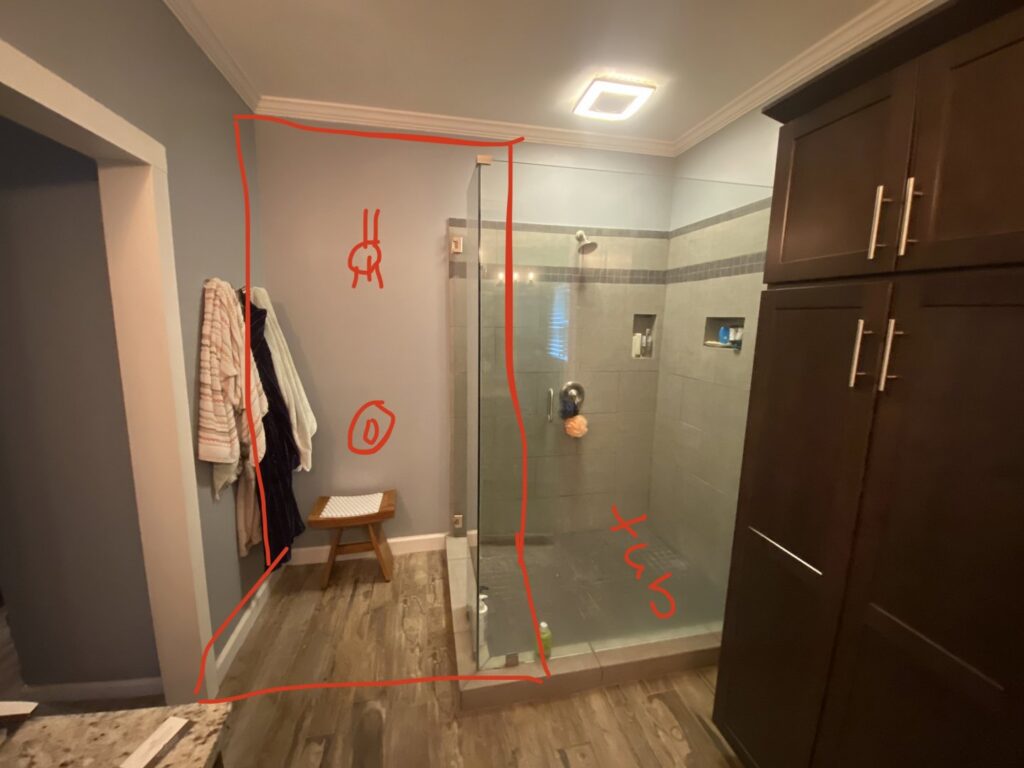 A bathroom renovation in the planning stage, showing a walk-in shower and red markings on the wall by Stonehedge Construction in Buford, GA