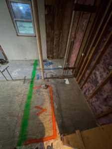 A bathroom renovation in progress, showing exposed plumbing, insulation, and floor markings for a new tub layout by Shackelford Home Designs in Loveland, OH.