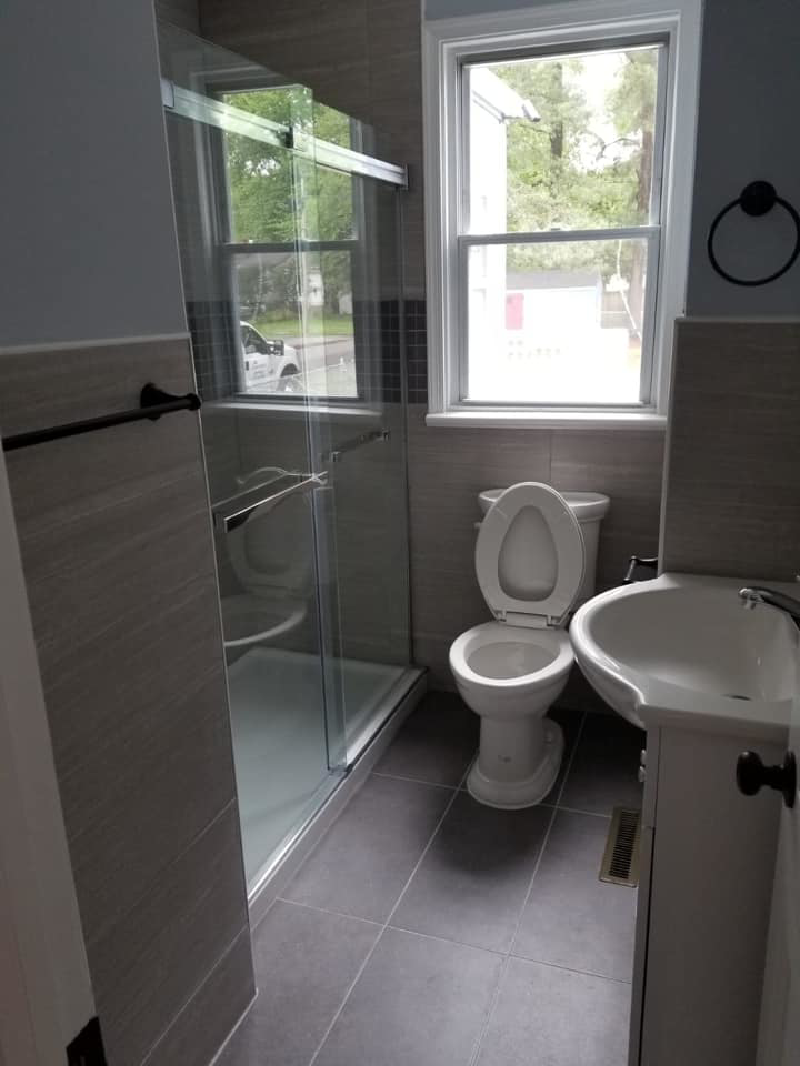 A complete bathroom renovation featuring a new shower, toilet, and sink by Professional Contractor RVA in Richmond, VA.
