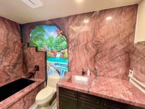 A renovated bathroom with custom stone walls, built-in tub, toilet, and stone vanity by Dorado Stone Inc. in Tucson, AZ.