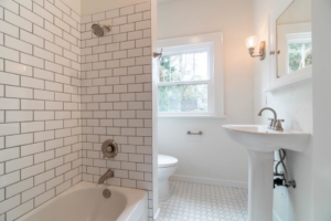 A newly renovated bathroom with a subway tile shower and pedestal sink completed by R2S Build in Eugene, OR.