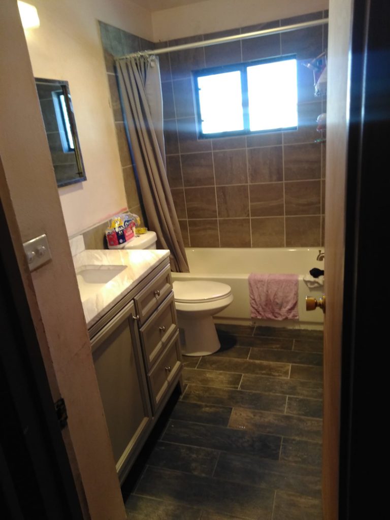 A newly renovated bathroom featuring dark tile flooring, a modern vanity, and tiled shower walls by MG'S Services LLC in Albuquerque, NM.