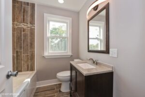 A renovated bathroom featuring new vanity, toilet, and wood-look tile shower surround by Grizzly Renovations in Naperville, IL