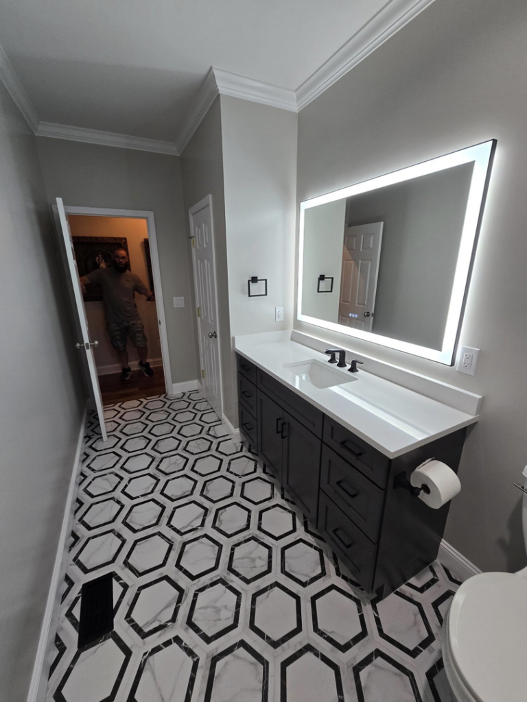 Stunning bathroom renovation with new hexagonal tile, vanity, and mirror by Hollis Construction in Nashville, TN.