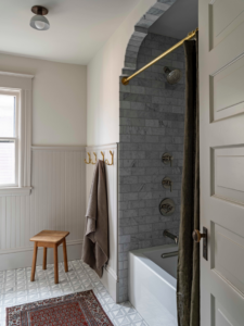 A beautifully renovated bathroom featuring a tiled shower and wainscoting by Tusk Builders, your handyman in Minneapolis, MN.
