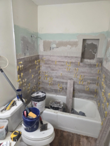 Bathroom renovation in progress with tiling tools and materials, showing services from Joel's flooring & Handyman services in Roy, UT.