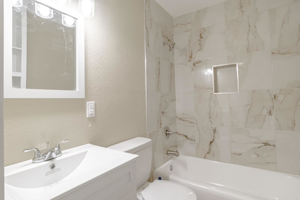 A beautifully renovated bathroom with new tiling, vanity, toilet, and tub installed by SSS Solutions, LLC in Mobile, AL.