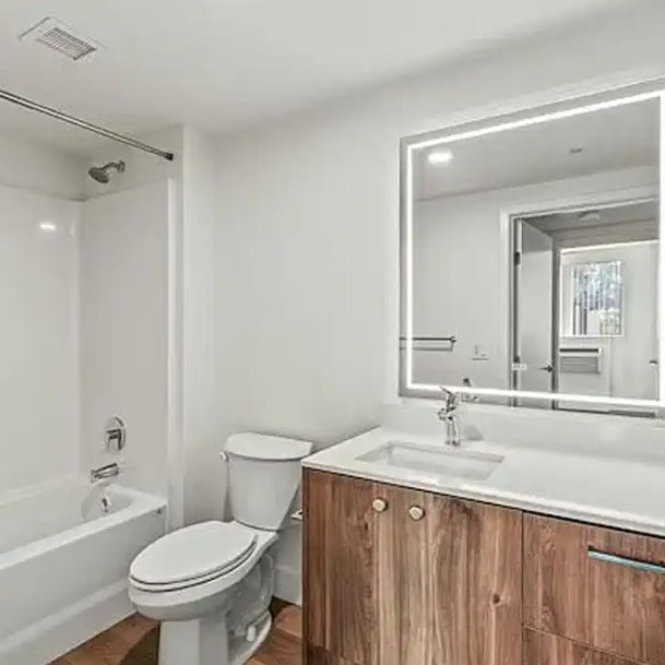 A modern bathroom renovation featuring a new wooden vanity and illuminated mirror by IM Construction LLC in Mount Vernon, WA.