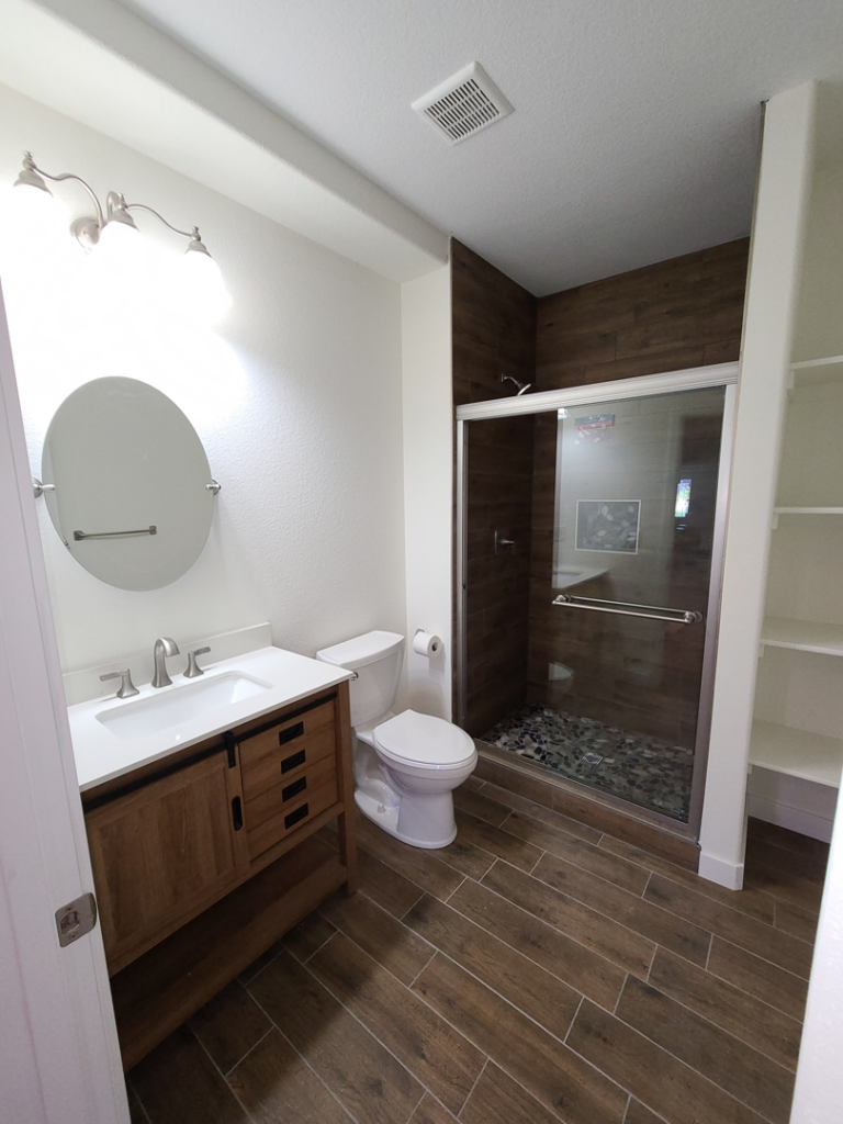 A modern bathroom renovation with a new vanity, toilet, and walk-in shower by QCON LLC in Aurora, CO.