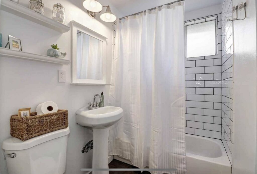 A renovated bathroom featuring a pedestal sink and a modern subway tile shower installed by The Sioux Falls Handyman in Sioux Falls, SD.