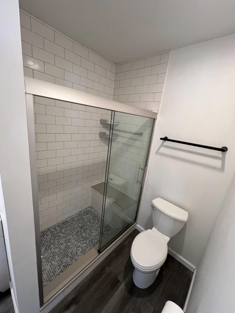 Completed bathroom renovation showing a new shower with glass doors and toilet by Roempagel Renovations LLC in South Bend, IN.