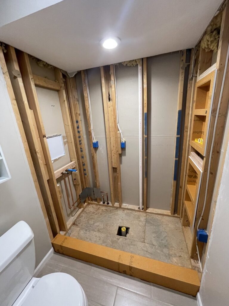 A bathroom shower area under construction, showing framing and plumbing work by Inspired Renovation & Hardscape's in Lorain, OH.