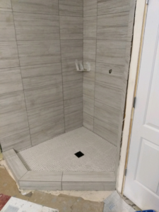 Detailed view of newly tiled shower curb and floor by J & D Home Innovations in West Jordan, UT