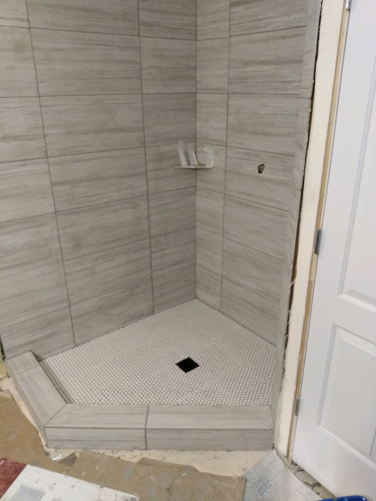 Detailed view of newly tiled shower curb and floor by J & D Home Innovations in West Jordan, UT