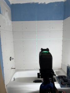 Bathroom shower area with drywall and a laser level for precise installation by High Plains Craftsmen in Cheyenne, WY.