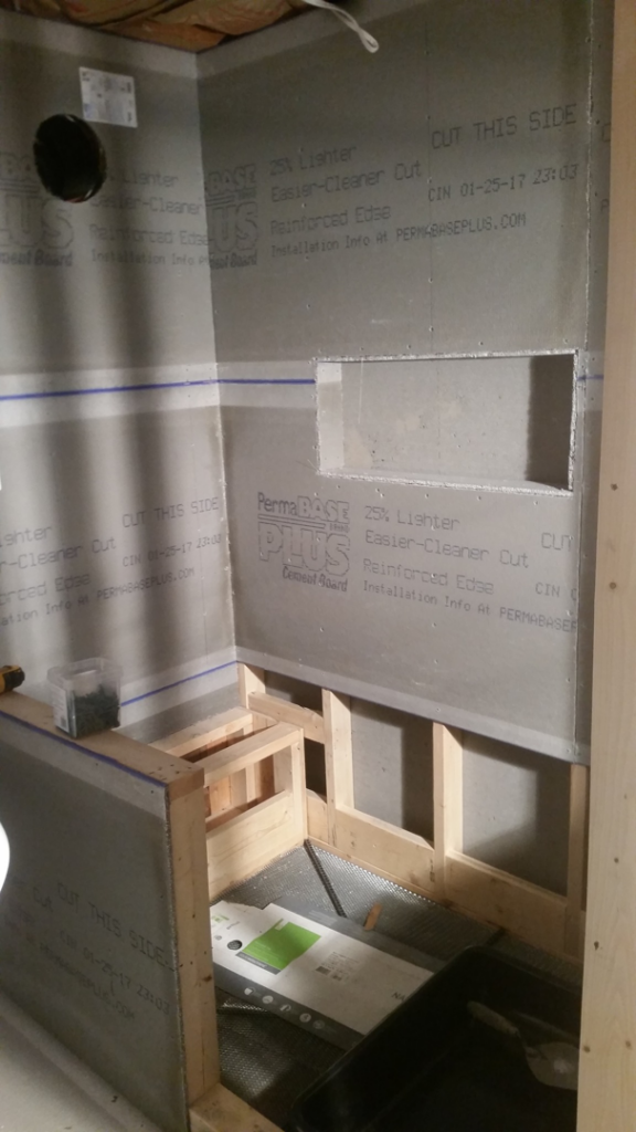 A bathroom shower under construction with cement board installed and wooden framing for a niche by Raleigh Renovations & Flooring in Cary, NC.