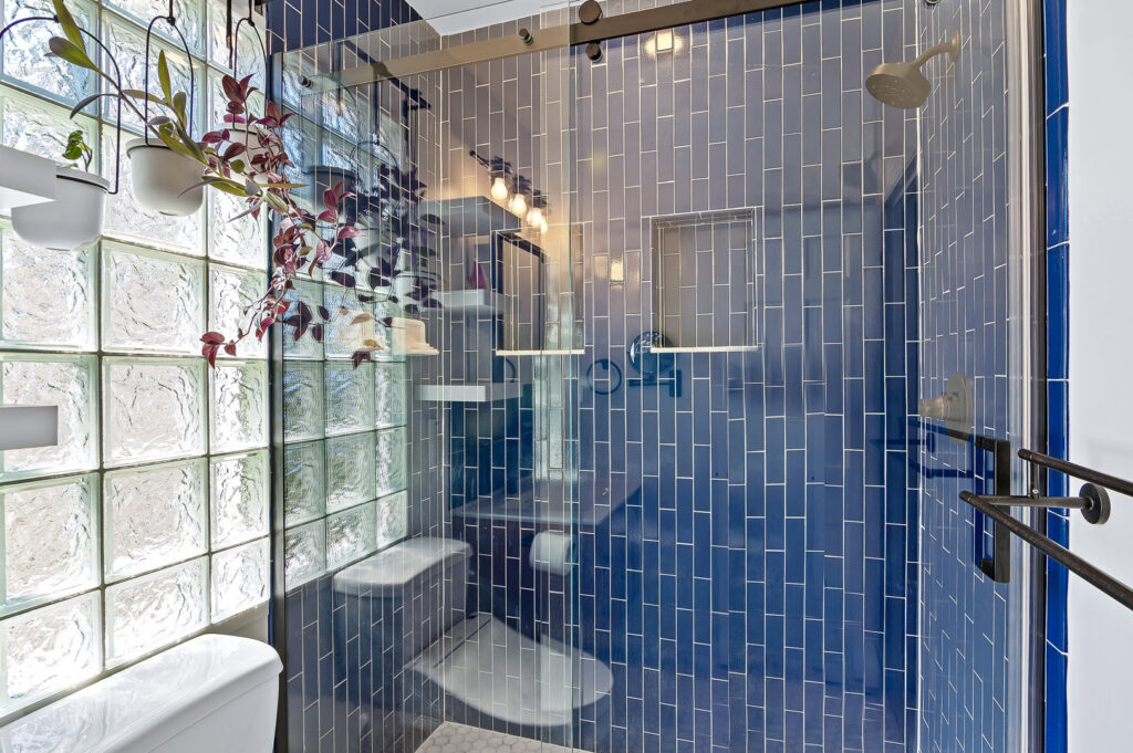 A renovated bathroom shower with blue subway tiles and a glass block wall by Total Craftsmen in Towson, MD