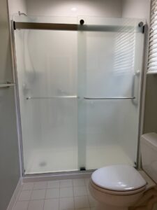A bathroom featuring a newly installed shower with a frosted glass sliding door by Peninsula Bath & Tile in Salisbury, MD.