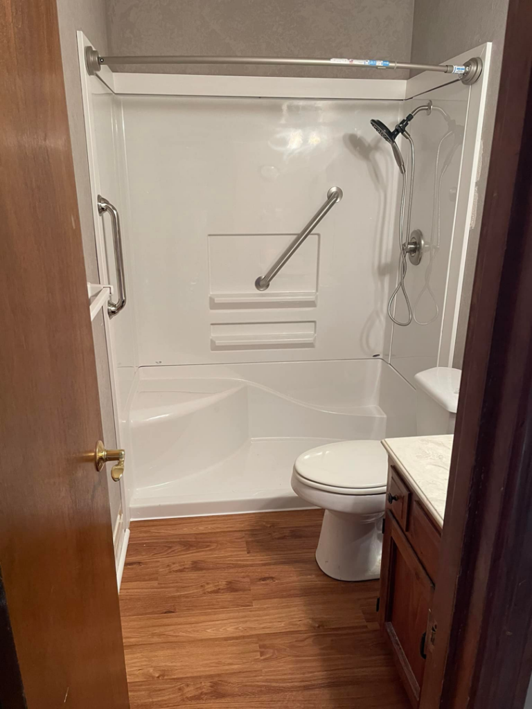 Newly installed shower unit with grab bars in a bathroom by Norbe's Home Solutions LLC in Lenexa, KS.